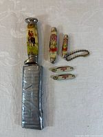 Group shot of five knives showing designs and sheath