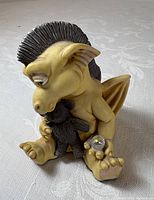 Front view of seated yellow dragon holding teddy bear and crystal orb