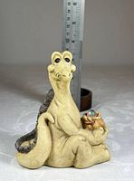 Front view of seated dragon figurine next to ruler showing scale