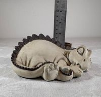 Left side view of sleeping dragon figurine with ruler for scale