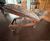 Side view adjustable gout stool showing frame, upholstery, casters, lever
