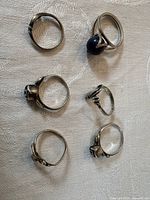 All six sterling silver rings displayed on fabric surface