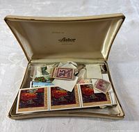 Open Astor jewellery case filled with assorted loose Canadian stamps