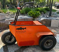 Side view of orange Nordskog personnel carrier showing wheels and cargo well