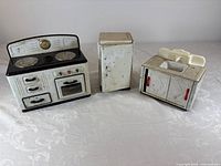 Three main toy kitchen units side by side: stove, fridge, sink
