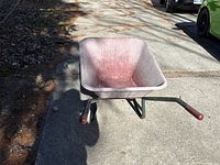 Top view of faded red wheelbarrow on driveway