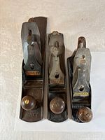 Top view of three Stanley Bailey hand planes showing lever caps and knobs