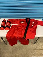 Full uniform laid out: jacket, pants, two guards