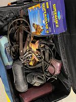 Open suitcase containing boxed SuperMask II fly mask, bridle with bit, lead rope, protective boots, paddock boots