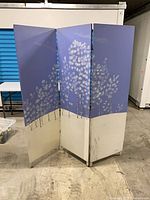 Front view of three-panel painted wood divider showing blue and white floral artwork