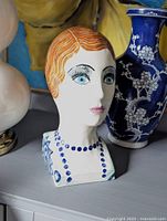 Front view of ceramic bust showing facial features and painted decoration