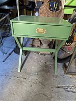 Front view of green side table showing drawer and brass pull