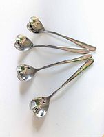 Four heart-shaped stainless steel spoons on white background