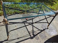 Full view of rectangular glass coffee table with metal frame and brass accents