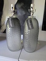 Two mottled grey glass table lamp bases with tags visible