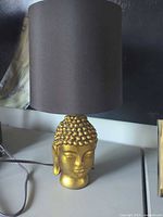 Front view of lamp showing Buddha head base and shade