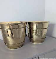Front view of both hammered brass planters