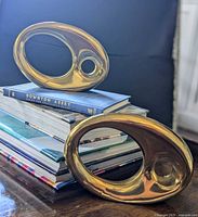 Both brass Ikebana vases on stacked books, front and back view