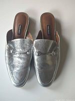 Pair of metallic silver Nine West backless loafer-style mules, top view