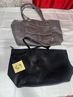 Grey croc-embossed handbag and black tote displayed on table