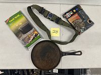 All four camping items laid out: pack grill, compressible pillow, cast iron skillet, nylon strap