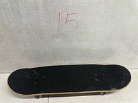 Top view of skateboard showing black grip tape and deck outline