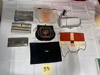 Eight assorted small purses arranged on white cloth showing fronts and size comparison