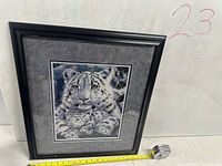 Front view of framed snow leopard picture with tape measure for scale