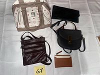 Group shot of five handbags and wallet laid out on white surface