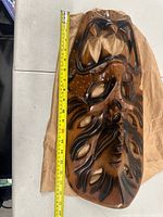 Full view of carved monkey pod wood mask with tape measure showing length