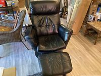 Front view of black leather recliner chair and ottoman showing upholstery and bases