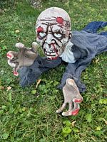 Front view of crawling zombie prop on grass