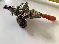 Full view of silver baby rattle showing coral handle and bells