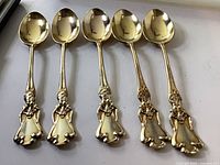 Front view of five gold-washed figural spoons