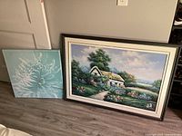 Both artworks leaning against wall to show size comparison and overall condition