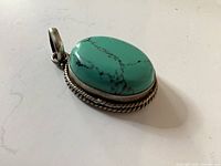 Front view of oval turquoise stone pendant in silver bezel