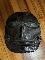 Front view of ceramic mask on wood floor