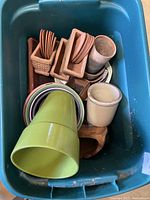 Assorted planters and saucers in bin