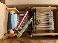 Loom in box, showing warp threads, shuttles, frame