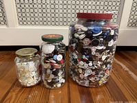 Three jars of buttons on wooden floor
