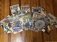 Overview of roughly 22 assorted bagged comics spread on floor