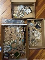Three boxes filled with assorted jewelry and travel clock
