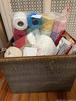 Wooden crate showing multiple coloured crochet cotton balls, plastic canvas pieces and accessories