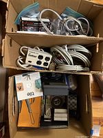 Two boxes containing surge bar, cords, boxed flasher, boxed switch, Tile tracker, tape, adapters
