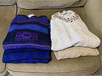 Two stacks of folded sweaters showing all three items