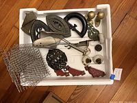 Overview of styrofoam tray with various metal pieces including iron, brackets, knobs, spoon, cage, wire mesh