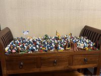 Full view of large collection of Smurf figurines spread across wooden bench