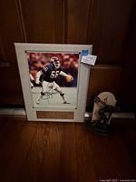 Framed Lawrence Taylor signed photo next to Olympic statue