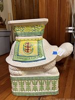 Left side view of ceramic turtle stool showing decorative panels and turtle head