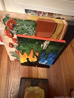 Stack of three unframed canvases showing floral, cat silhouette and abstract paintings